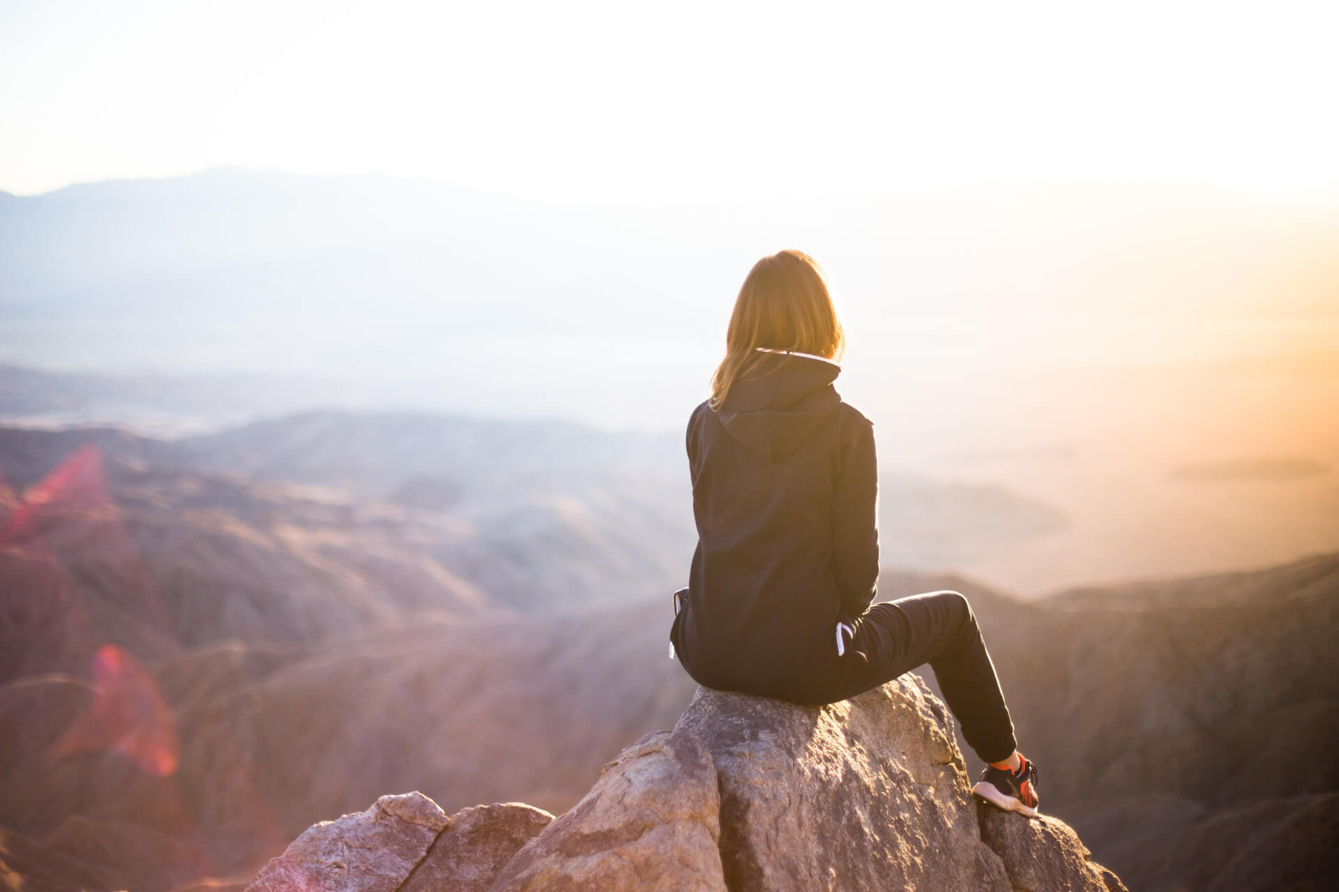 Une femme est assise au sommet d'une montagne après une longue escalade.